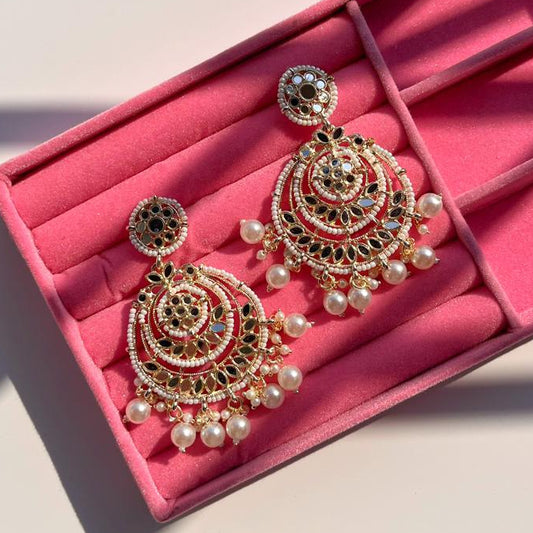 Ornate earrings with pearl accents on a pink jewelry box