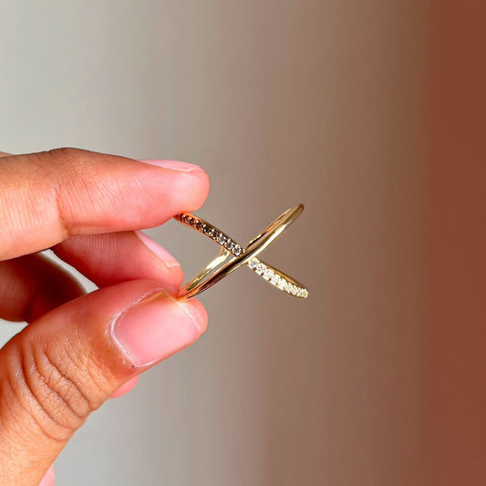 Gold Infinity Ring held by a hand against a gradient background