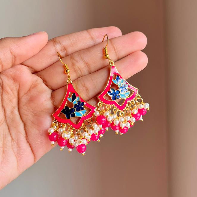 Hand holding a pair of colorful earrings with a blurred background