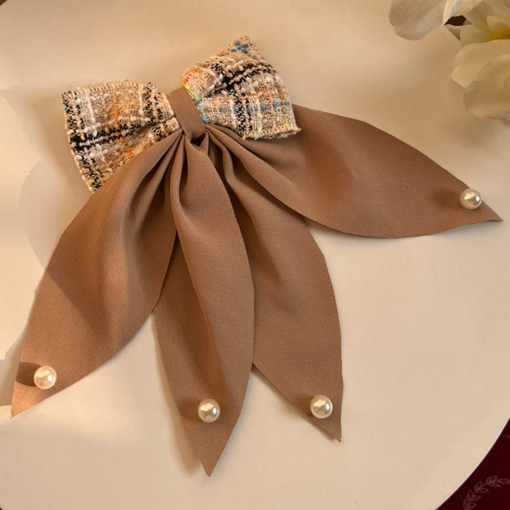Bow Clip on a white plate with flowers in the background.