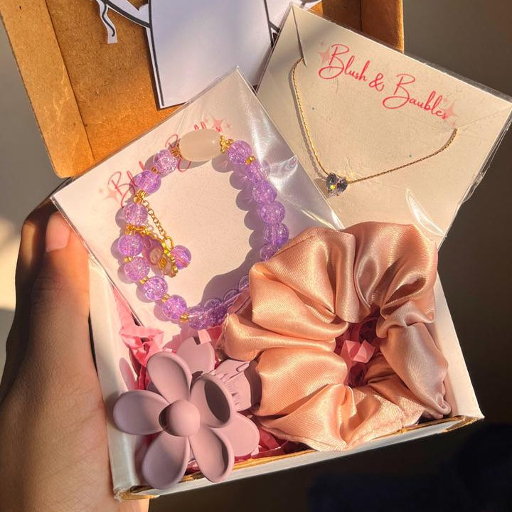 Gift box with decorative items including a hair bow, necklace, and card.