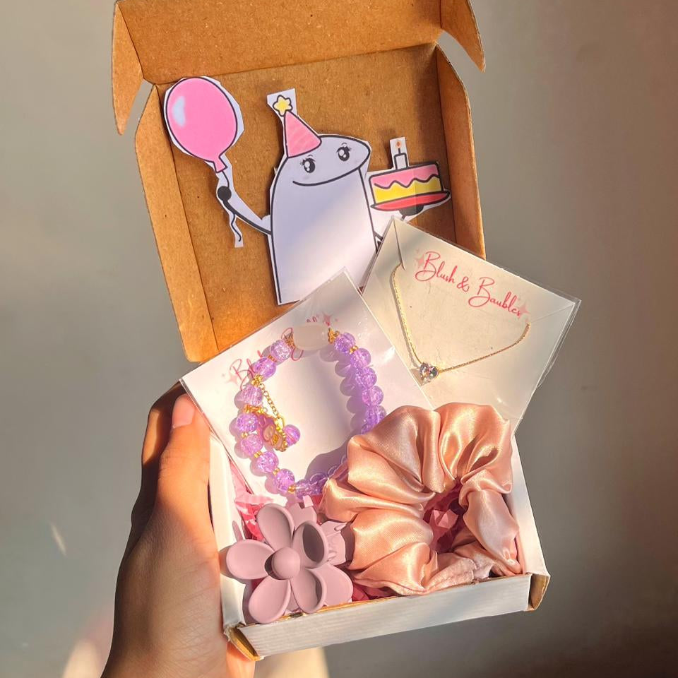 Gift box with hair accessories and a jewellery, held by a hand against a neutral background