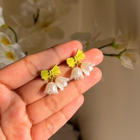 Hand holding a pair of floral earrings with a blurred background