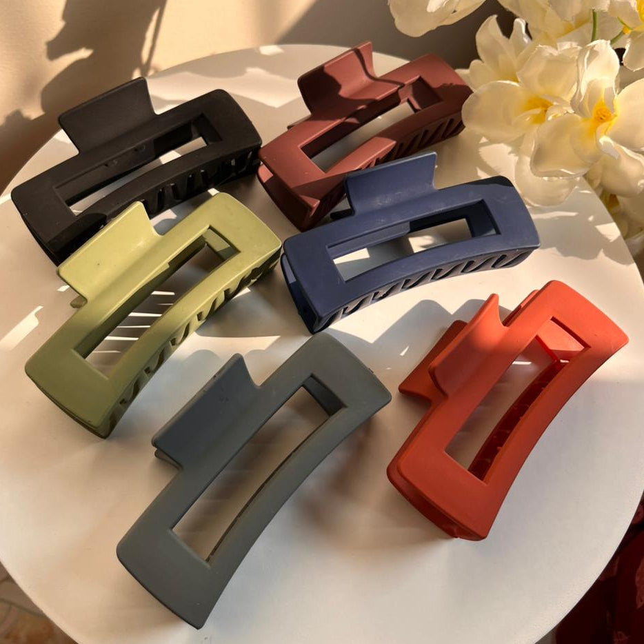 Set of colorful hair clips on a white surface with flowers in the background