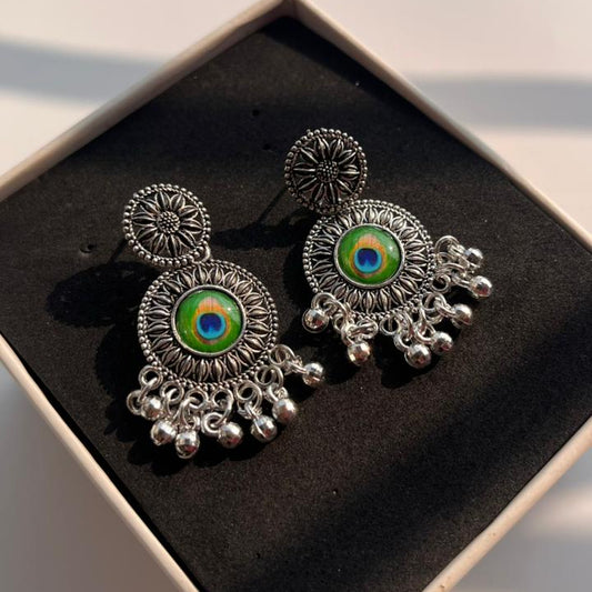 Ornate earrings with colorful centers in a black box on a light surface