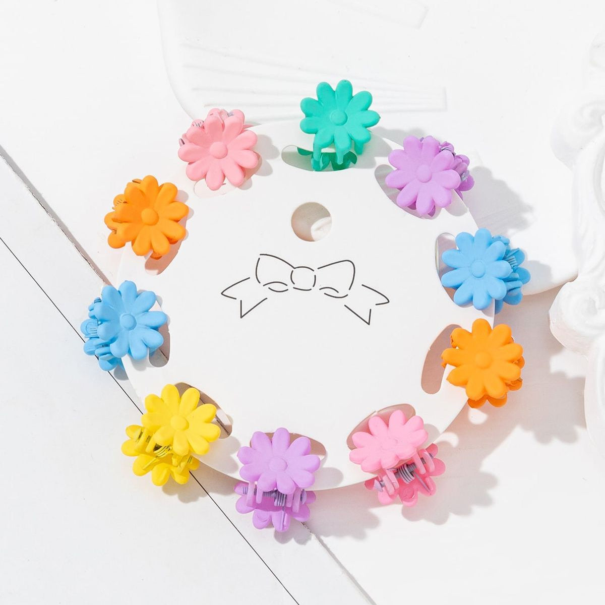 Colorful flower-shaped hair clips on a white surface with a bow design.