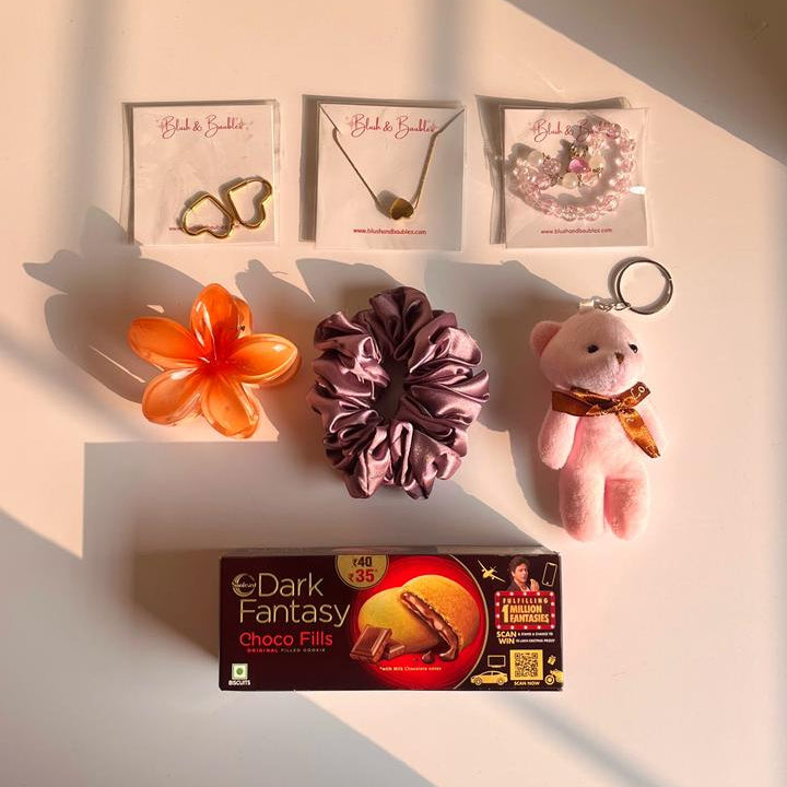 Collection of small items including a flower, hair tie, keychain, and box on a white surface.