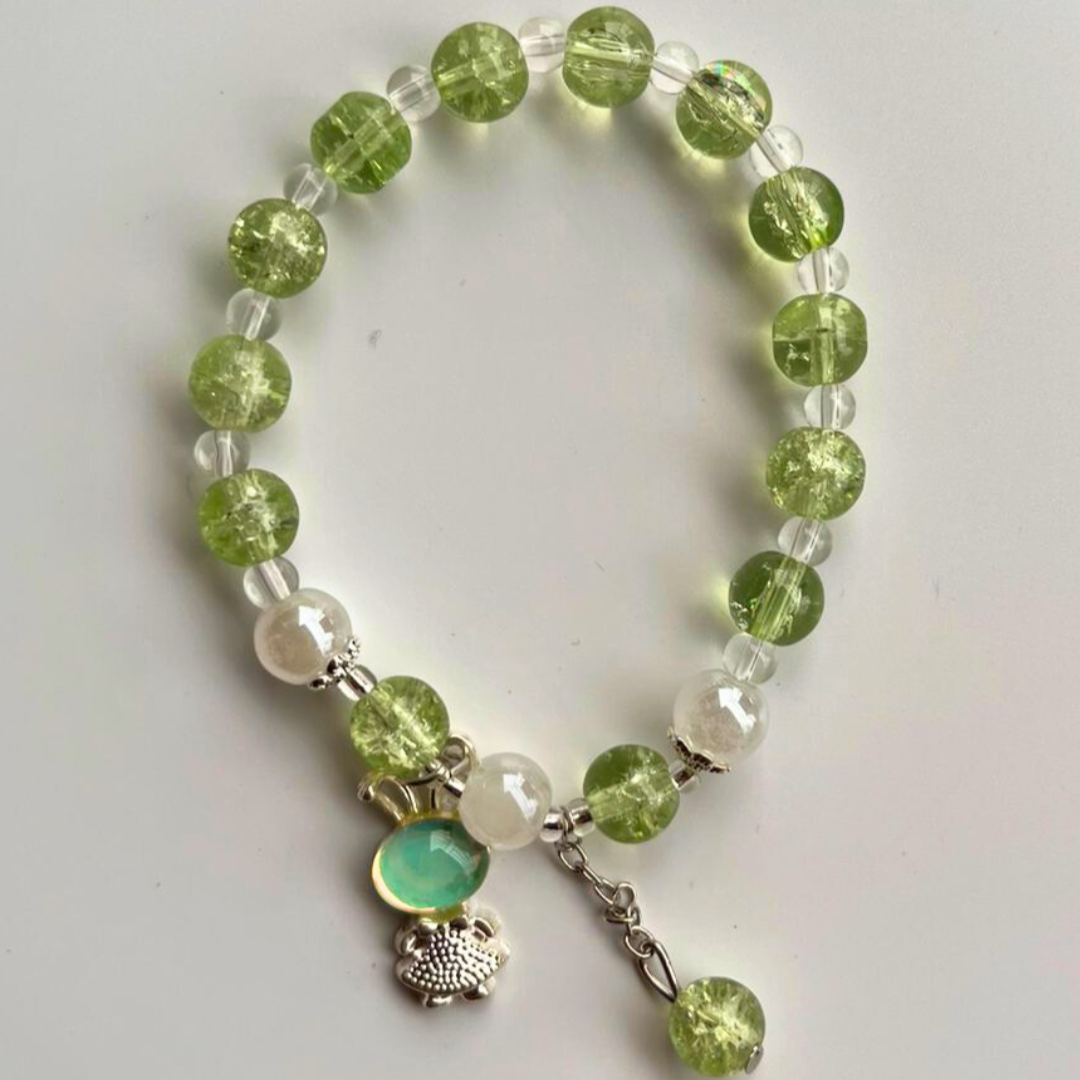 Beaded bracelet with green and clear beads on a white background