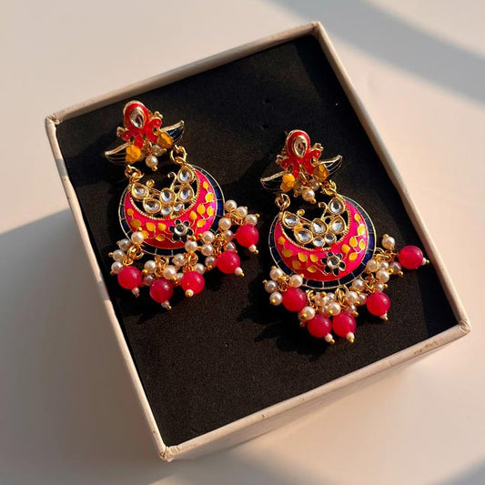 Box having a pair of meenakari earrings with intricate designs against a neutral background