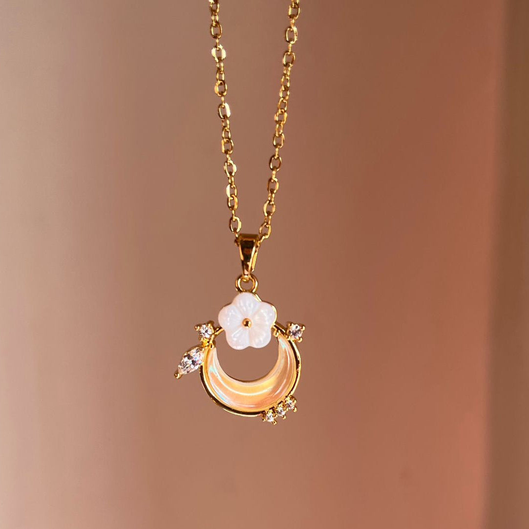 Gold necklace with a floral pendant on a brown background