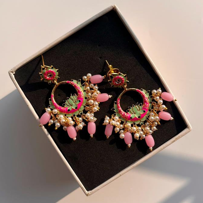 Pair of pink and gold earrings in a box on a light background