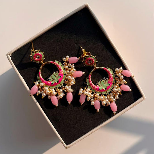 Pair of pink and gold earrings in a box on a light background