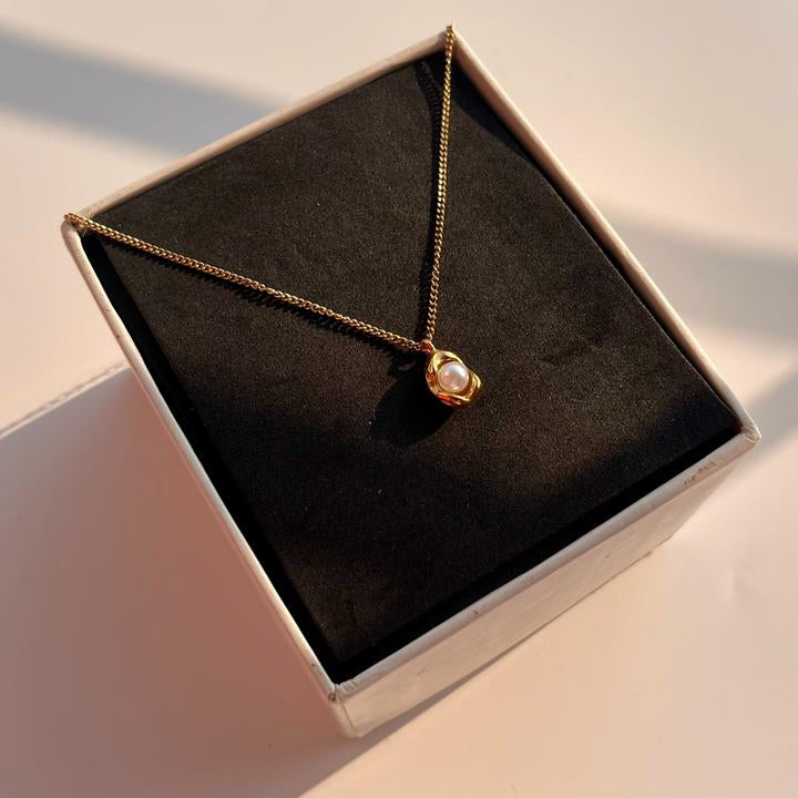 Necklace with a pendant in a black jewelry box on a light surface