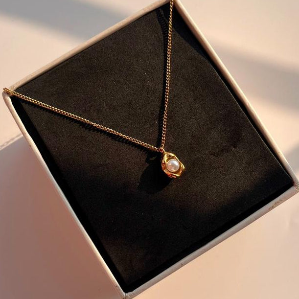 Necklace with a pendant in a black jewelry box on a light surface