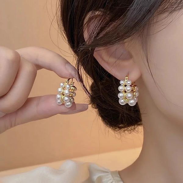 Pearl earrings being worn on an ear with a blurred background