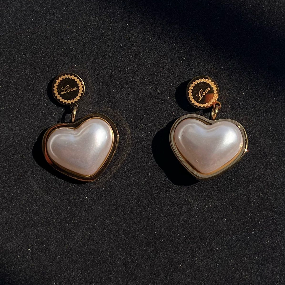 Heart-shaped earrings with gold accents on a black background