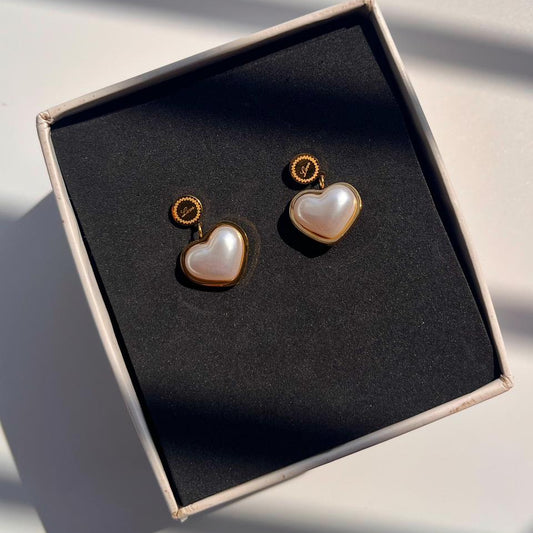 Heart-shaped earrings with pearl-like finish in a box on a light background