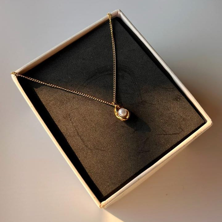Necklace with a pendant in a box on a neutral background