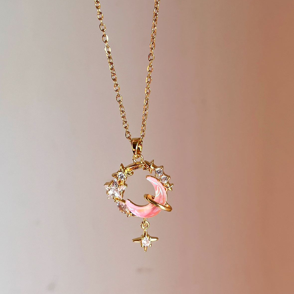 Gold necklace with a pink pendant on a gradient background
