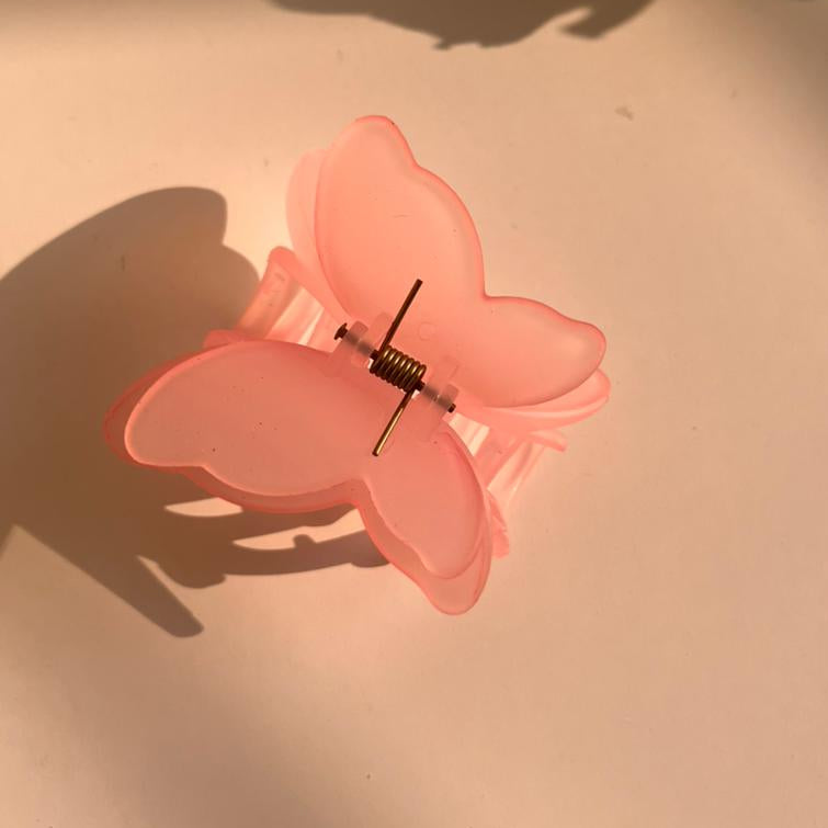 Pink butterfly hair clip on a beige surface
