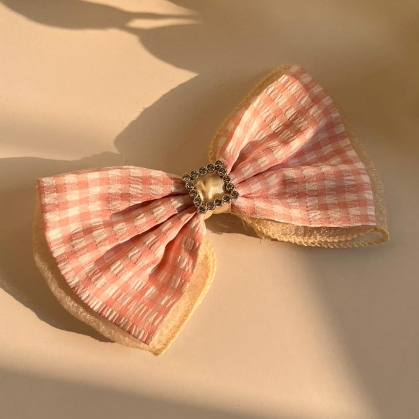 Pink checkered bow on a beige surface with a soft focus background