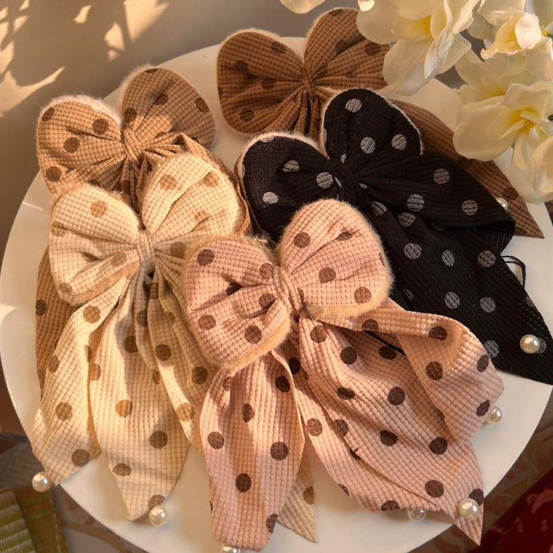 Set of decorative bows with polka dots on a white plate, surrounded by flowers.