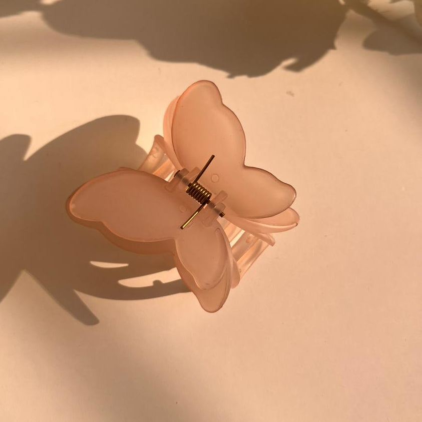 Butterfly-shaped hair clip on a light surface with floral background