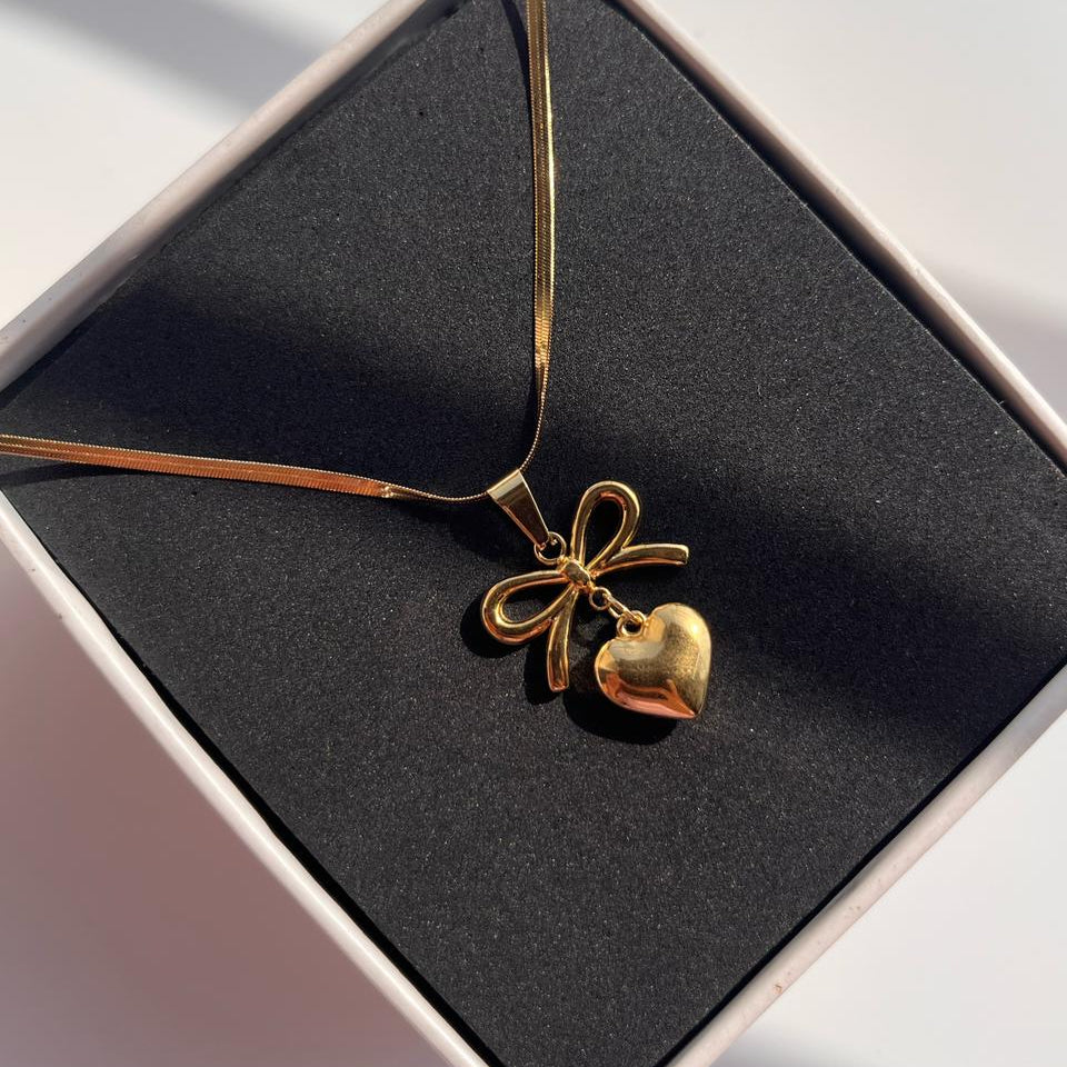 Gold necklace with a heart pendant on a black box