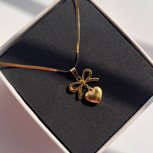Gold necklace with a heart pendant on a black box