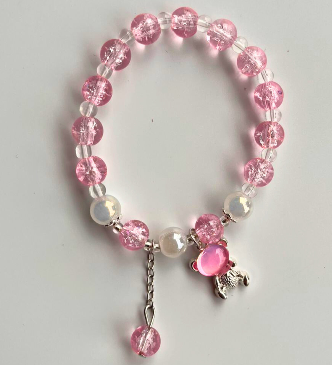 Bracelet with pink and white beads and a silver charm on a light gray background