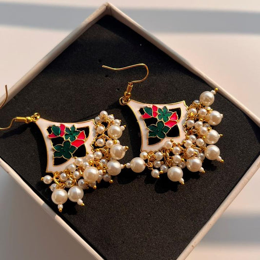 Decorative earrings with pearls and gemstones on a black box