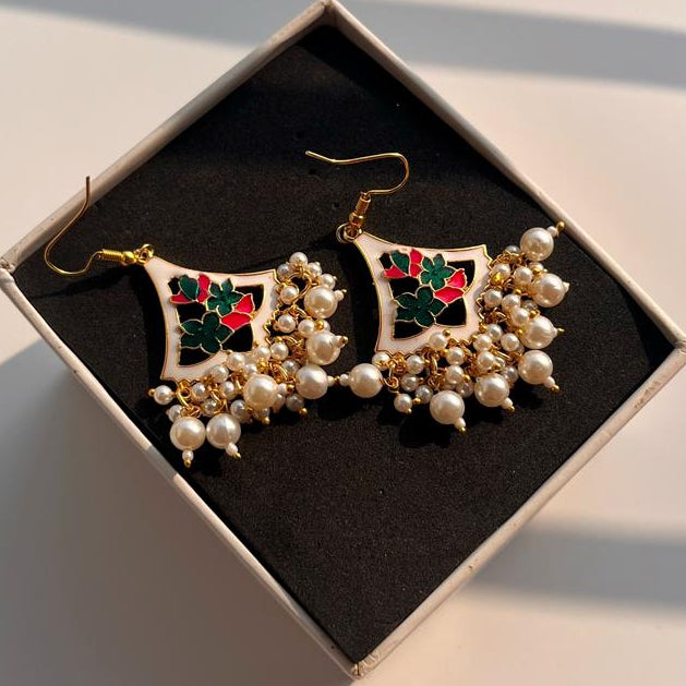 Pair of pearl and gemstone earrings in a box on a light surface