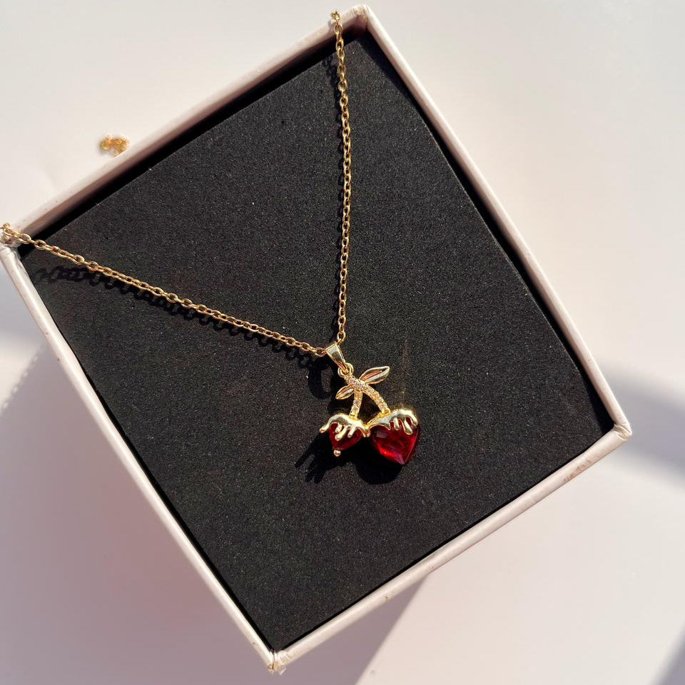 Necklace with a cherry pendant in a box on a light background