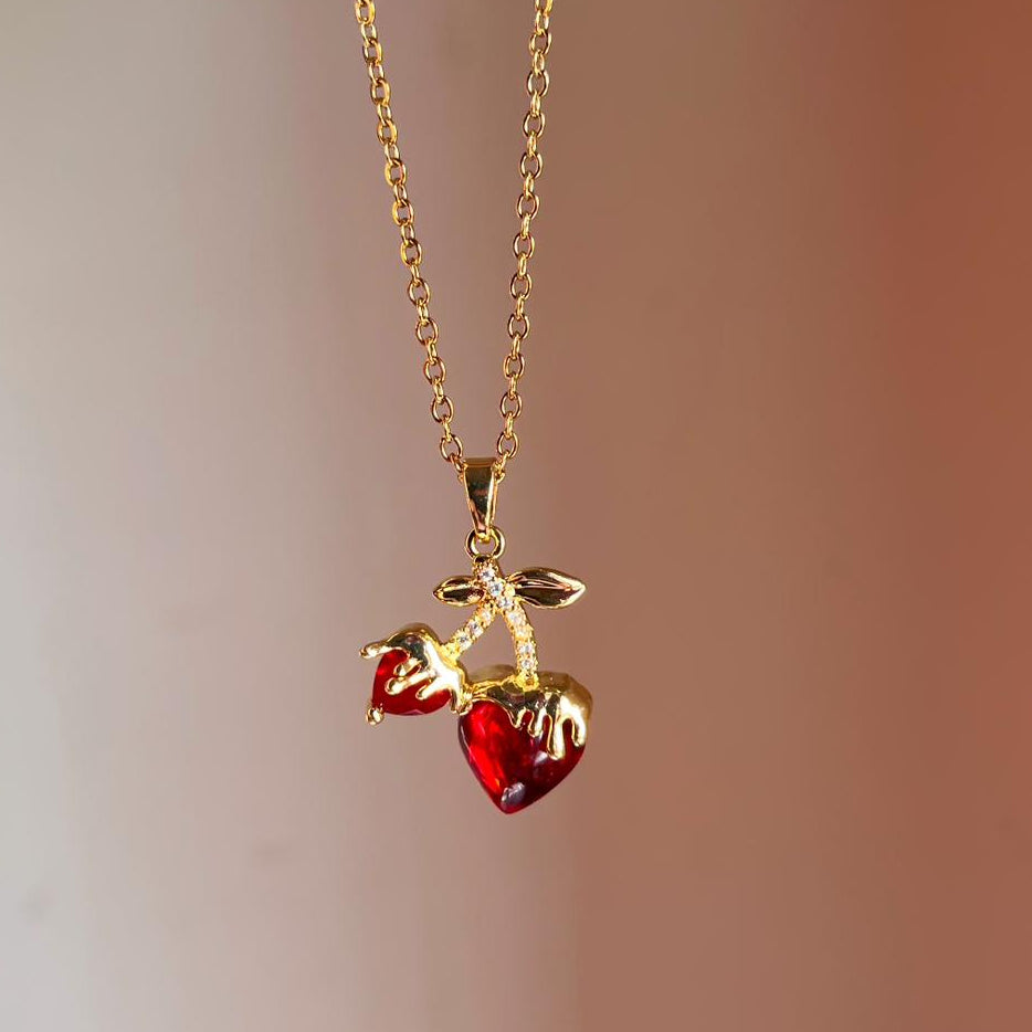 Gold necklace with red heart pendants on a blurred background