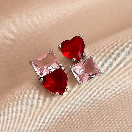 Pair of earrings with red and pink gemstones on a beige background