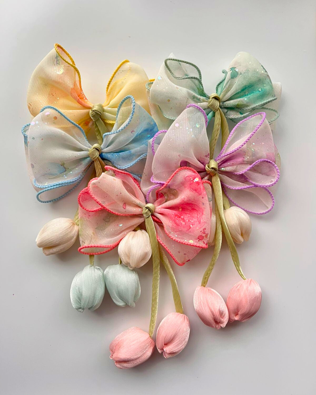 Colorful fabric bows with flowers on a light gray background