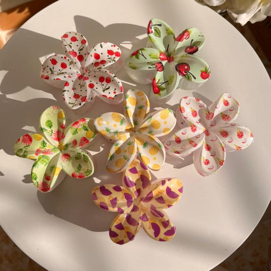 Decorative floral hair clips with colorful patterns on a white plate.