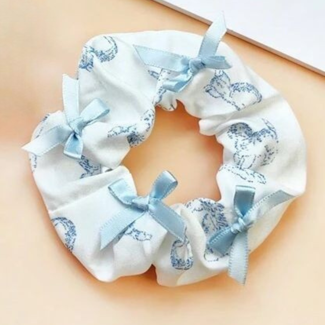 White scrunchie with blue floral patterns and ribbons on a beige background