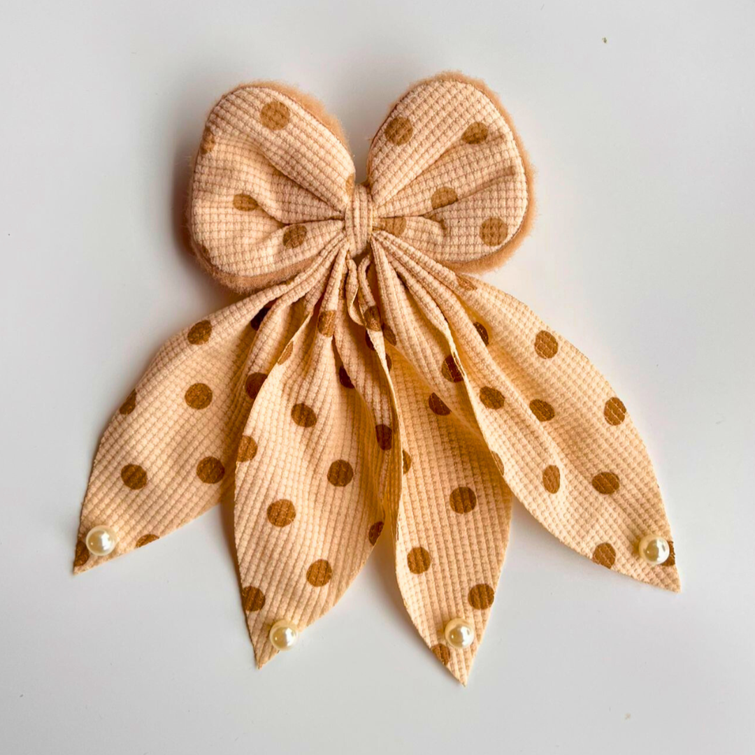 Beige bow with gold polka dots on a light gray background