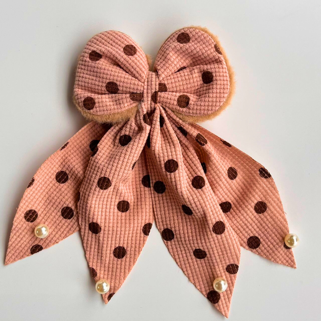 Pink polka dot bow hair accessory on a light gray background