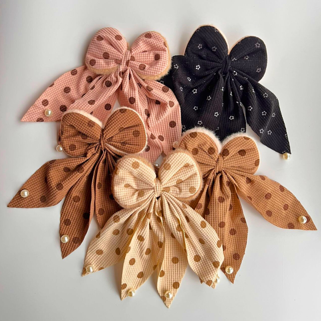 Set of five polka dot bows in various colors on a light gray background