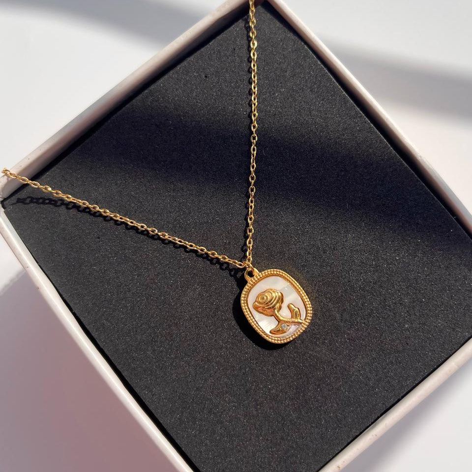 Gold necklace with a pendant in a black jewelry box on a light background