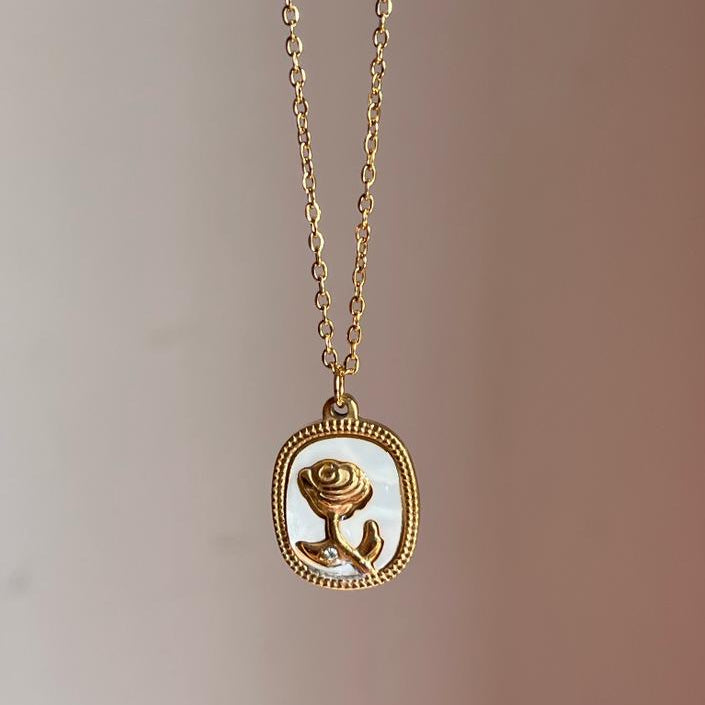 Gold necklace with a rose pendant on a blurred background