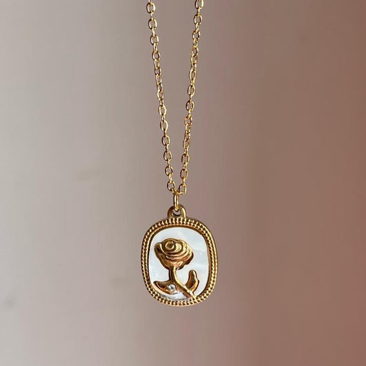 Gold necklace with a rose pendant on a blurred background