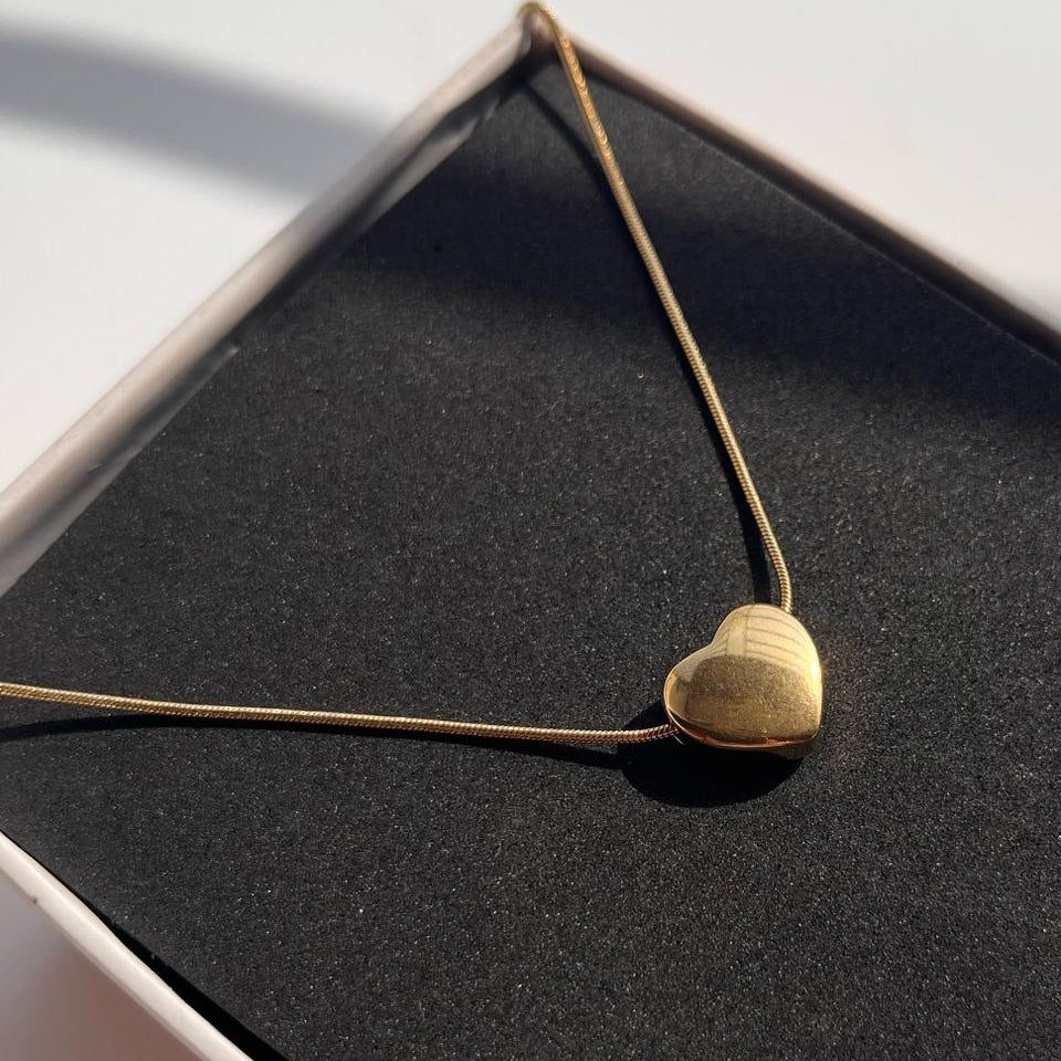 Gold heart-shaped pendant necklace on a black surface