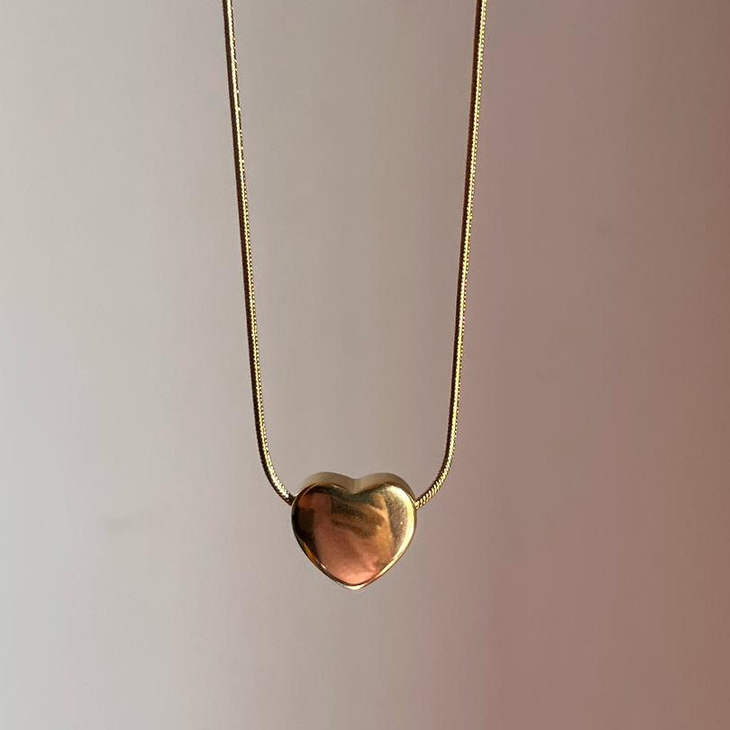 Gold heart-shaped pendant on a thin chain against a plain background