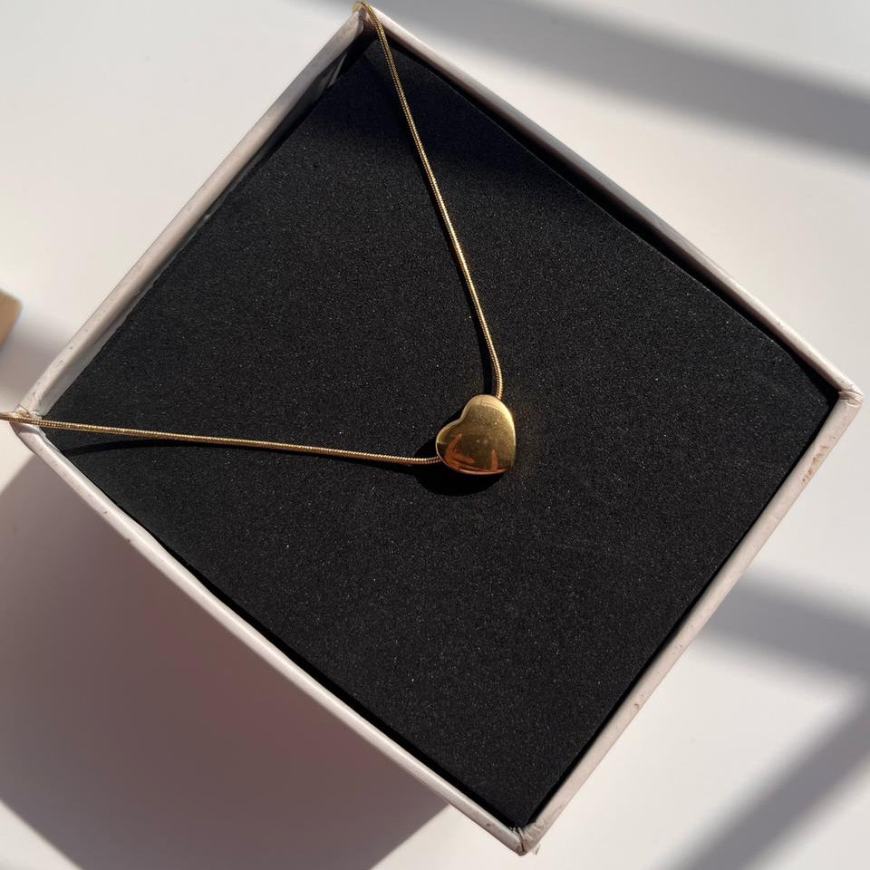 Gold heart-shaped necklace in a black box on a light surface