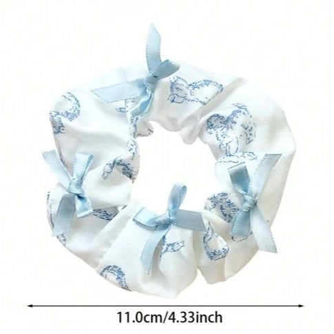 White scrunchie with blue patterns and bows on a white background