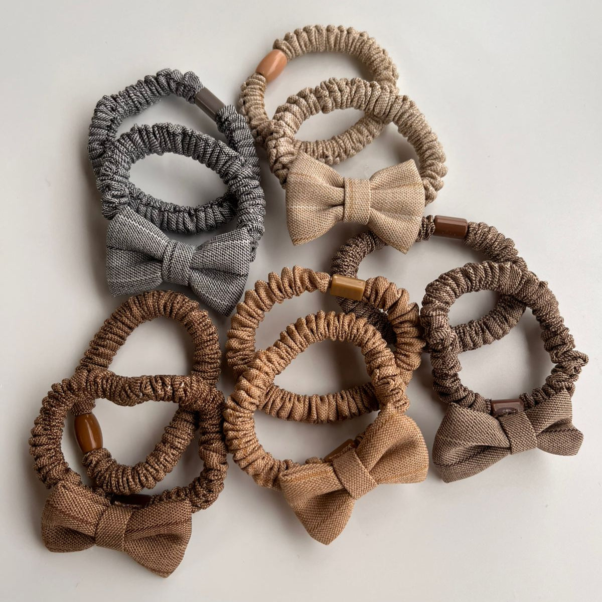 Set of hair scrunchies with bows in various shades of brown on a light background
