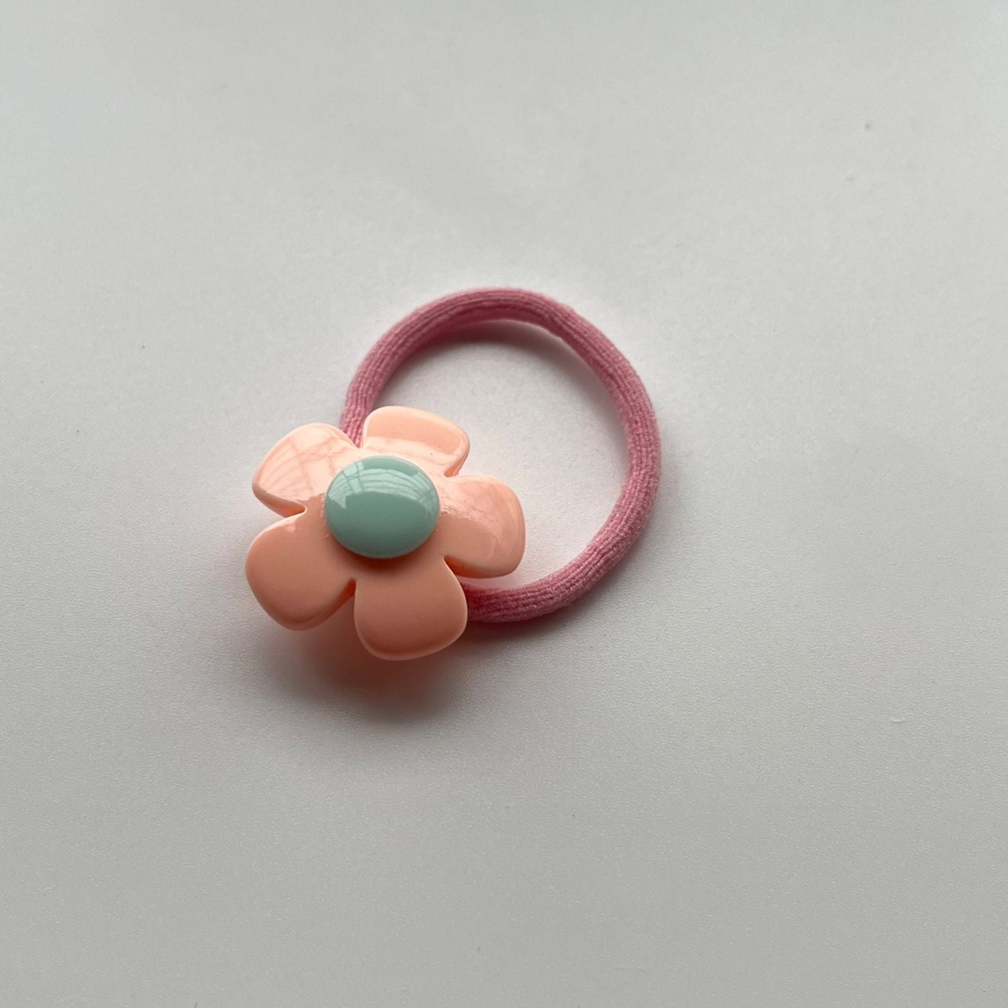 Pink hair elastic with a floral design on a light gray background